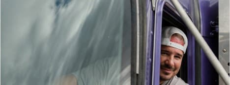 Professional commercial truck driver smiling from cab window